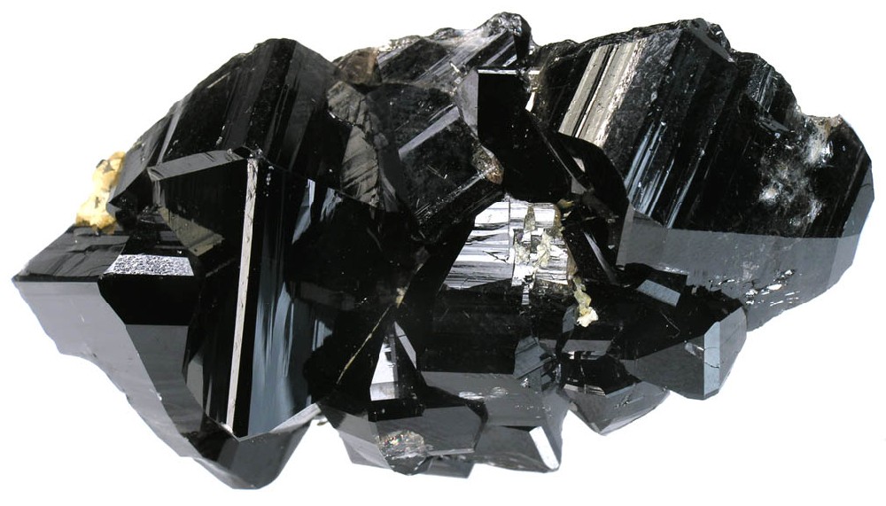 A cluster of glossy black cassiterite crystals on a white background